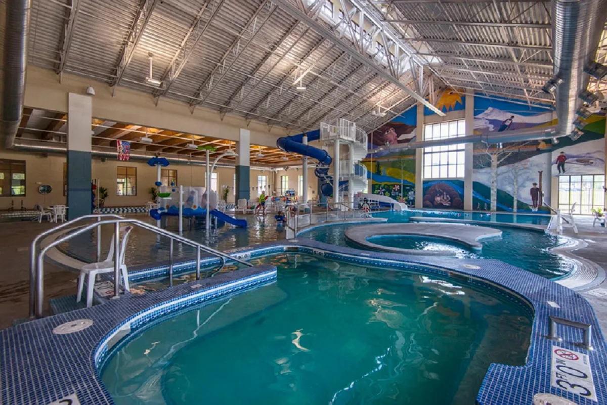 A vibrant indoor water park area with colorful water slides, swimming pools, and children playing joyfully. The lively environment conveys excitement, making it perfect for families and groups looking for nearby activities.