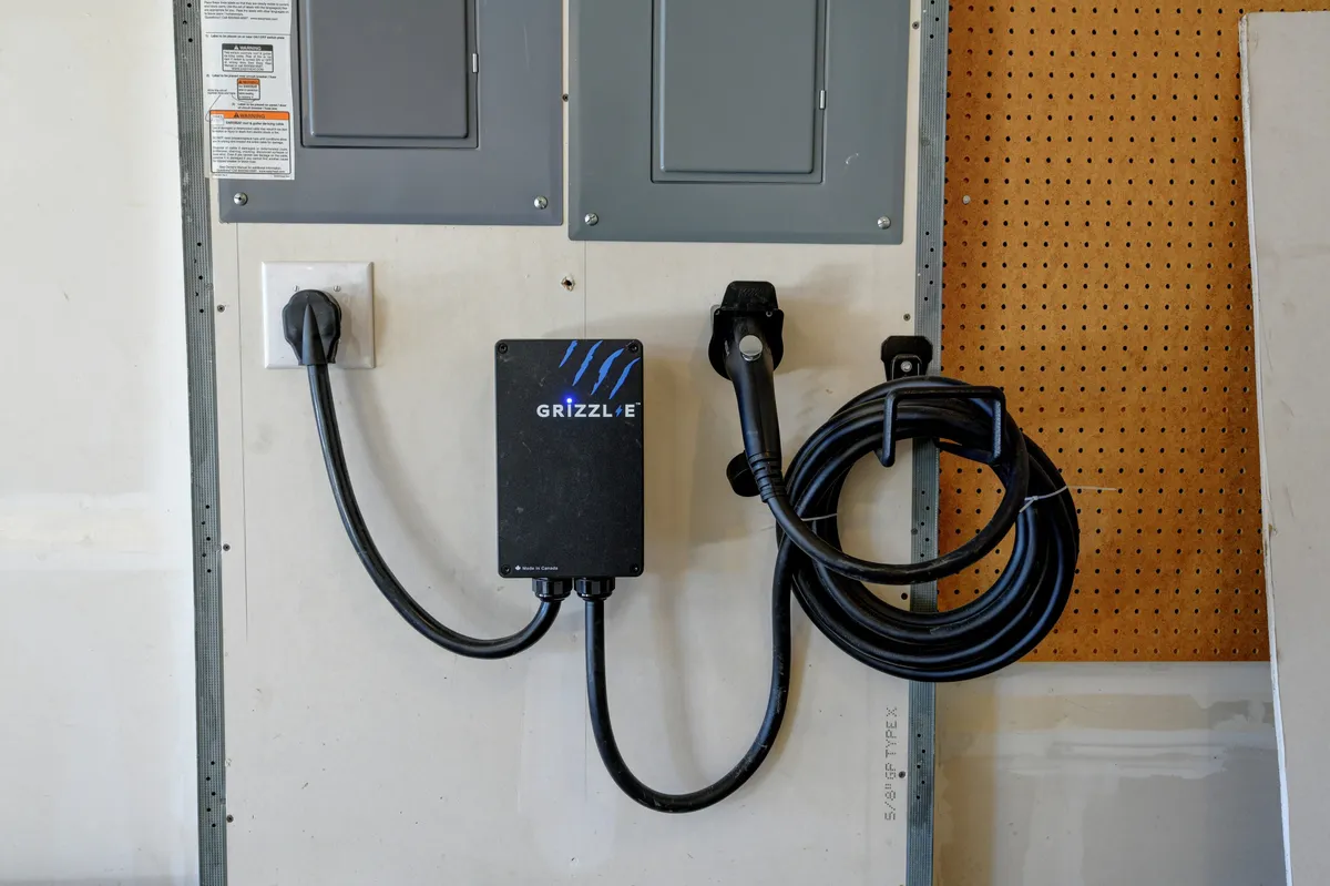 A dedicated charging station for electric vehicles in the home's garage area, complete with power outlets and modern technology. The space is clean and functional, emphasizing convenience for guests with e-cars.
